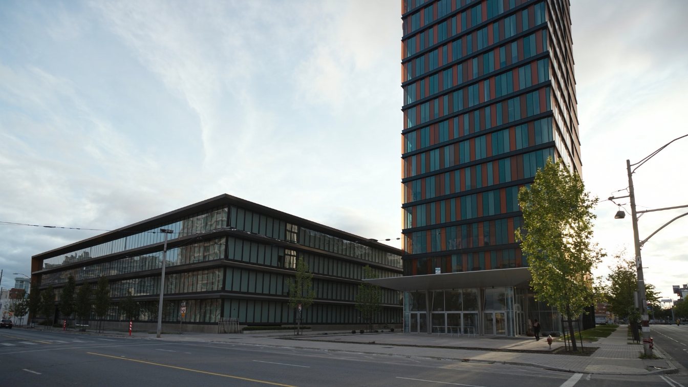Mid-rise condominium tower with coloured glass panels beside a modern public library at a downtown Toronto corner (illustrative)