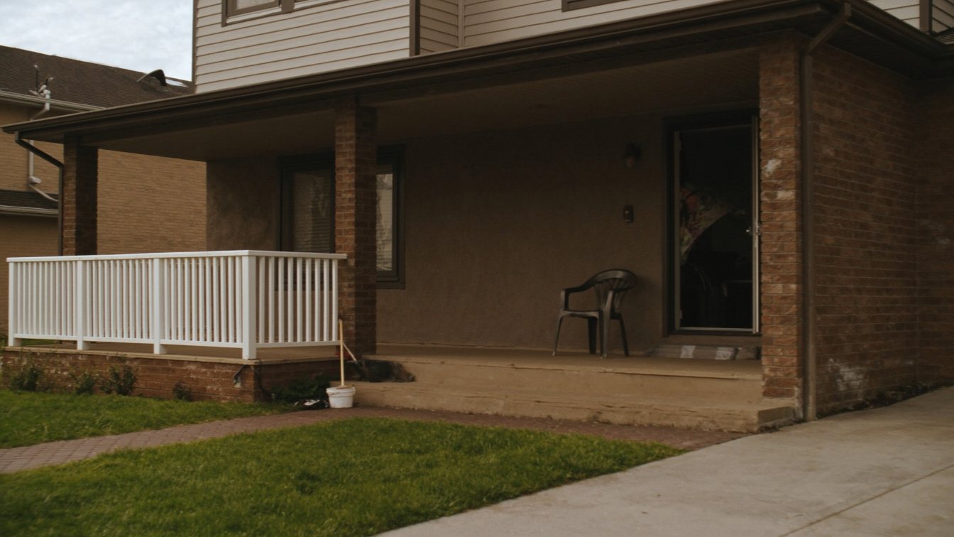 Homeowner on the front steps with papers outside a GTA house (illustrative)