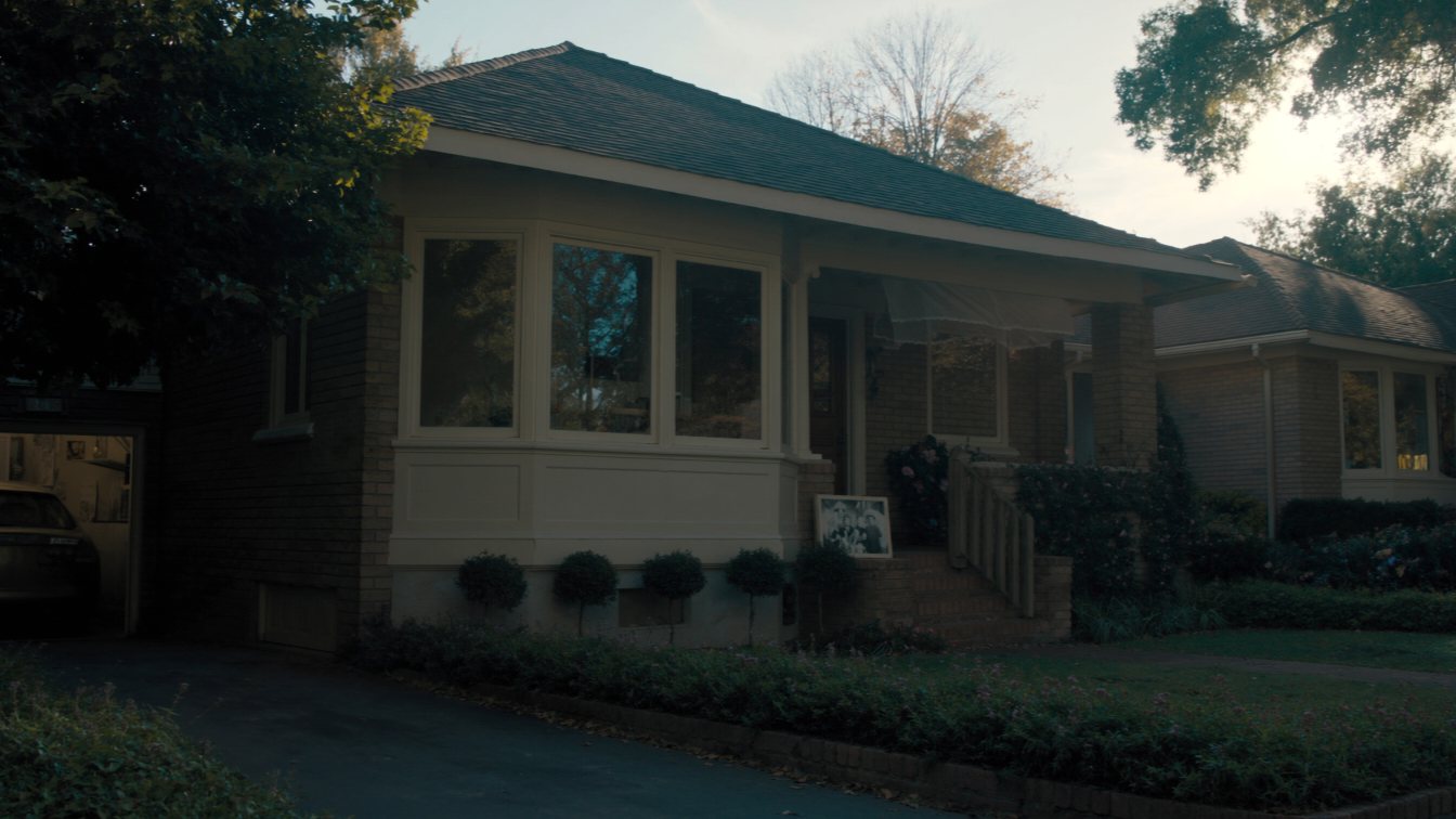 Older brick bungalow with a box of family photos on the step (illustrative)