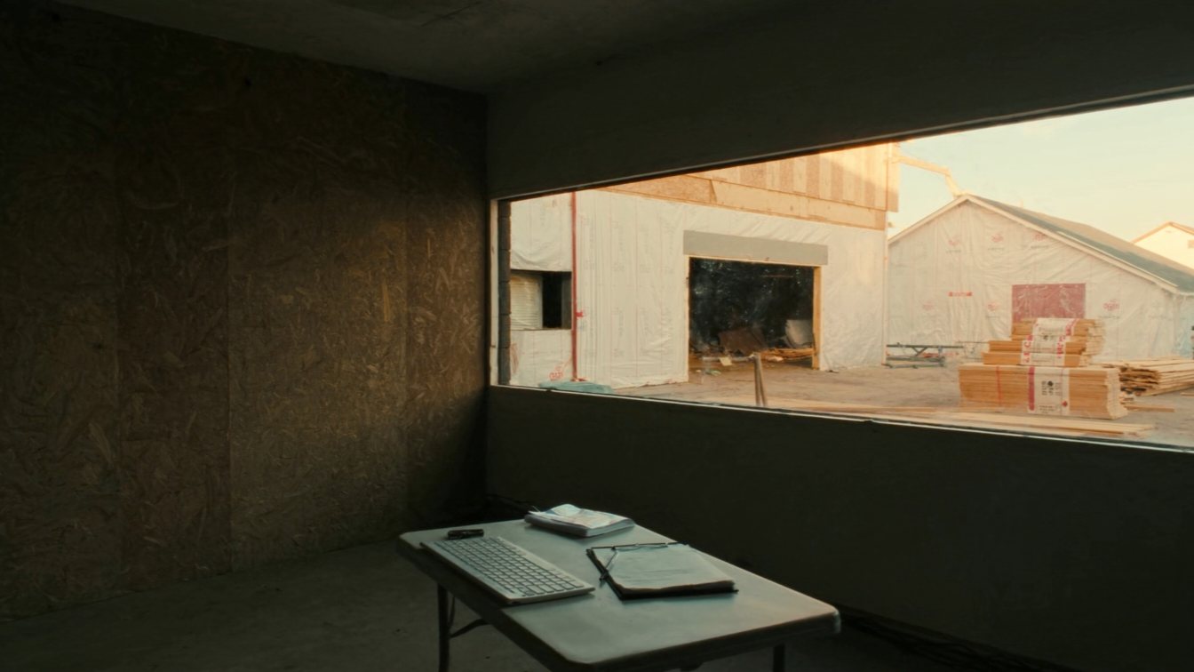 New house under construction with a deposit cheque book in the foreground (illustrative)