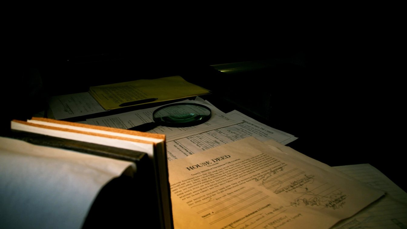 Property title documents under a magnifying glass (illustrative)