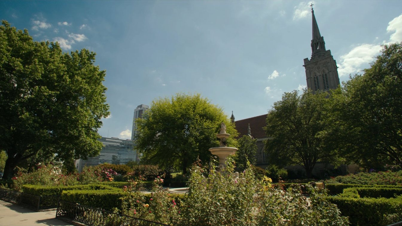 Victorian-style garden with a tiered fountain and flower beds beside a Gothic cathedral in downtown Toronto (illustrative)