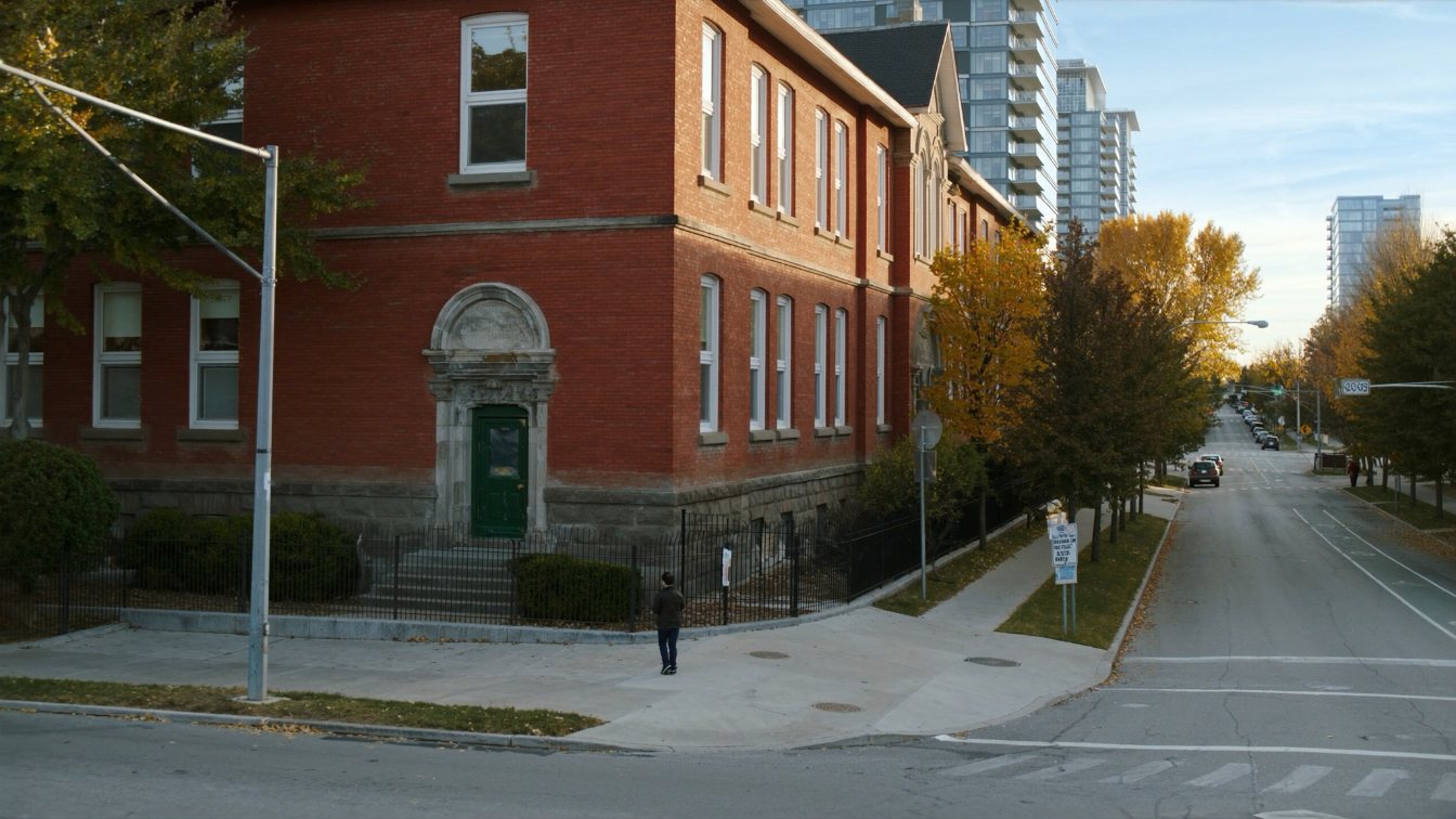 Red-brick public school building on a tree-lined street near King Street West condominium towers in Toronto (illustrative)