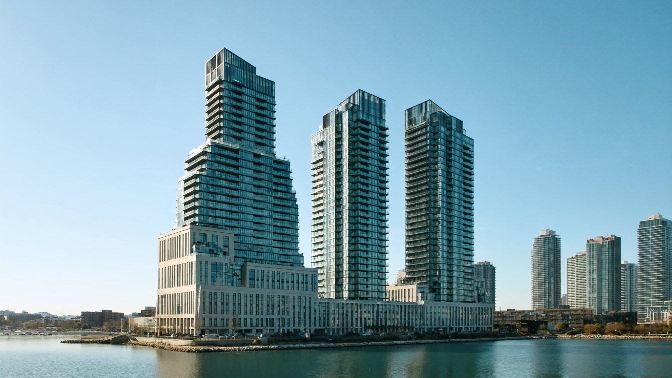 Three glass condominium towers on the Toronto waterfront along Queens Quay West, seen from the lake (illustrative)